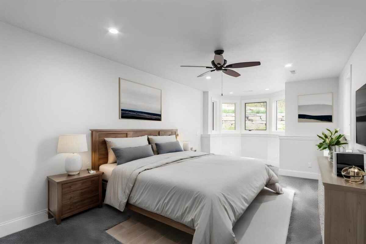 Second bedroom includes a bay window, ceiling fan, and modern furnishing with natural light.