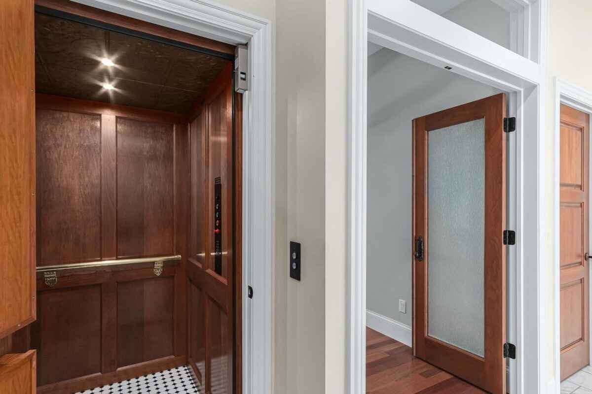 Elevator includes wood paneling, brass accents, and black-and-white tile flooring.