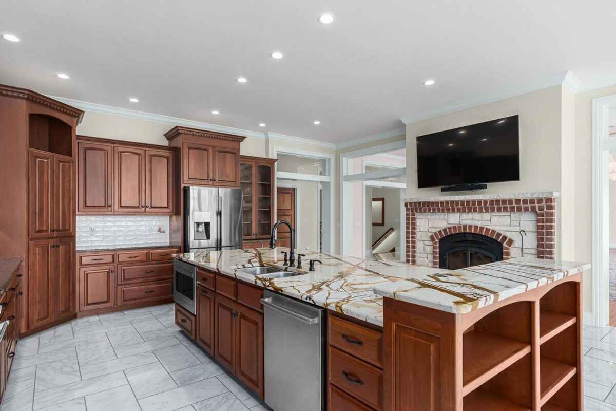 Secondary view of the kitchen highlights a fireplace, integrated appliances, and spacious layout.