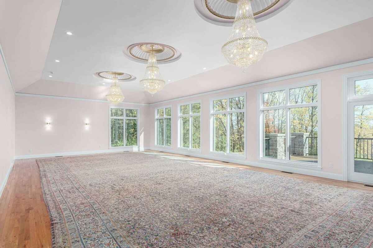 Grand room features floor-to-ceiling windows, chandeliers, and an expansive area with hardwood flooring.