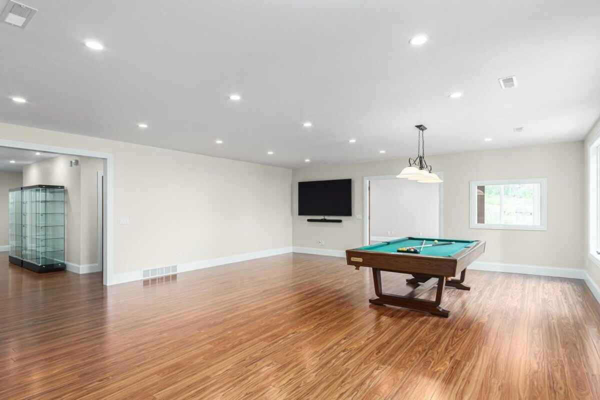 Game room with hardwood floors, a pool table, and a large flat-screen TV mounted on the wall.