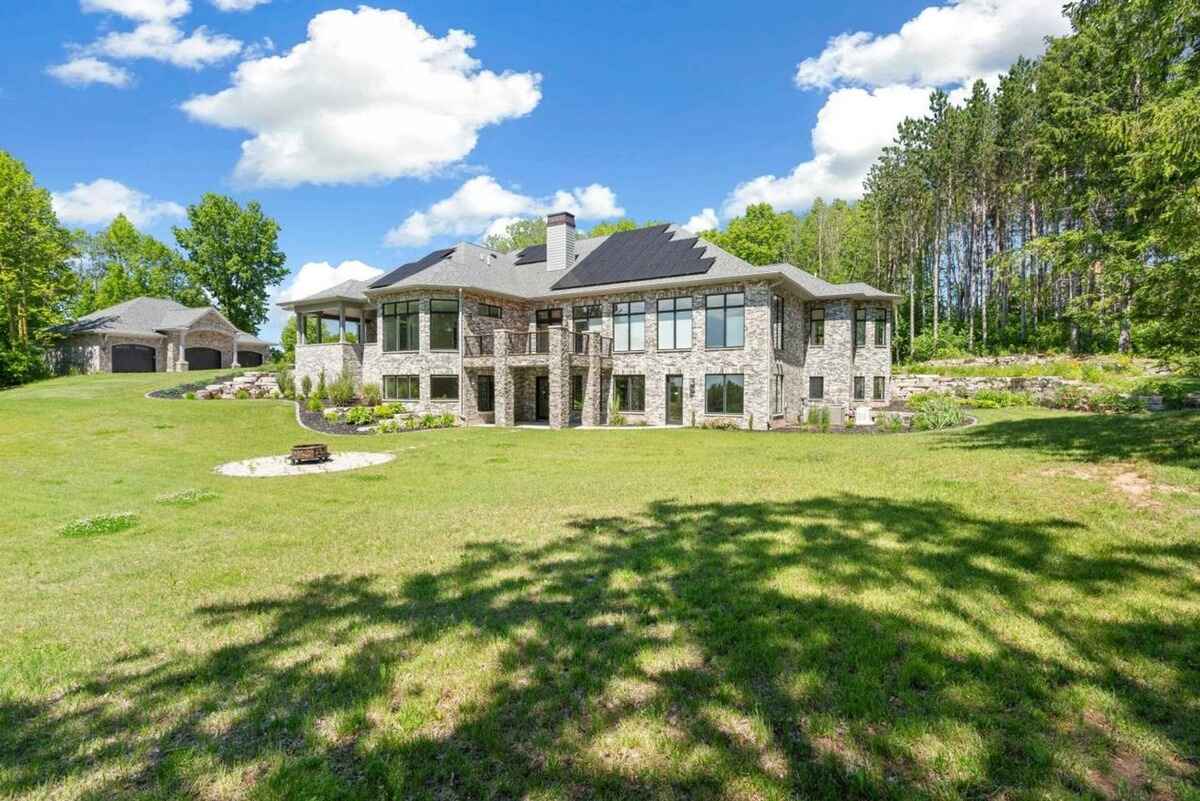 Back elevation highlights the large windows, covered patios, and multi-level layout with wooded surroundings.