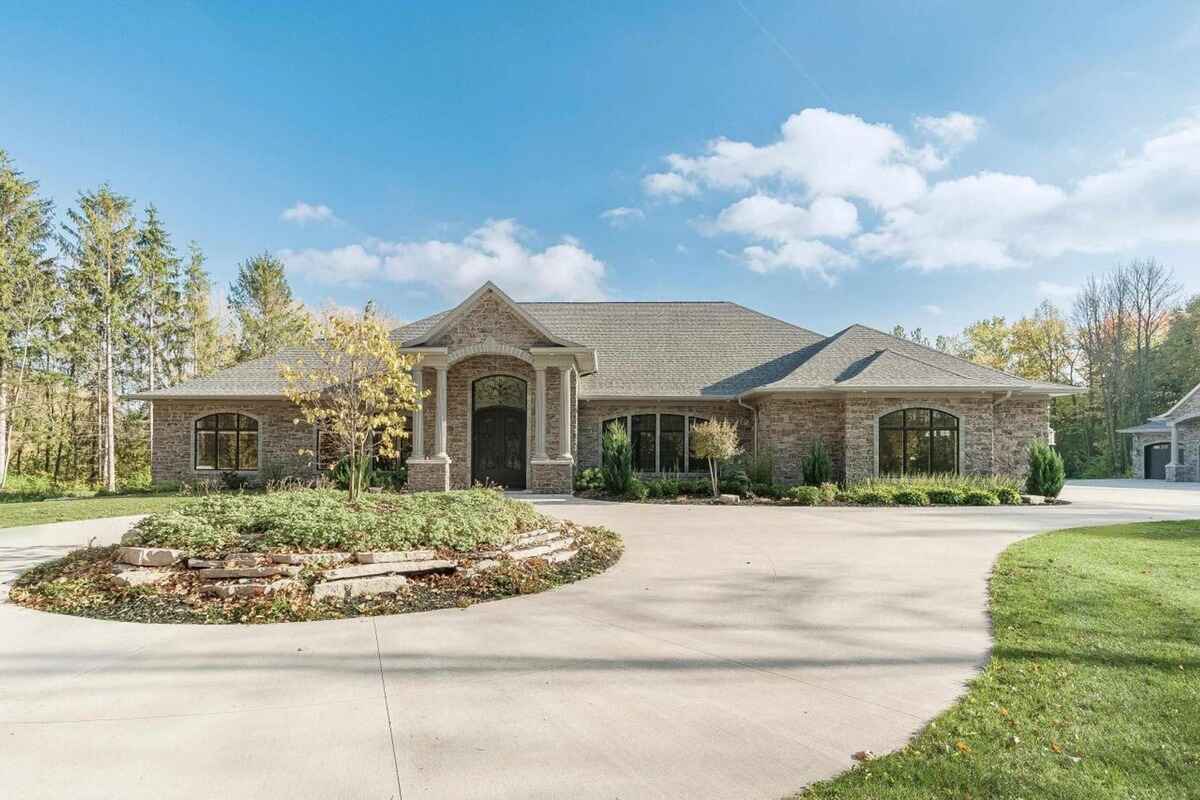 Front angle of the house features a landscaped roundabout driveway and large arched windows.