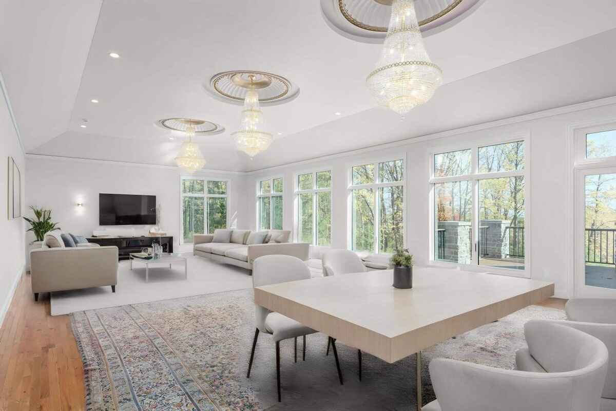 Living room features large windows, chandeliers, neutral-toned seating, and views of the surrounding greenery.