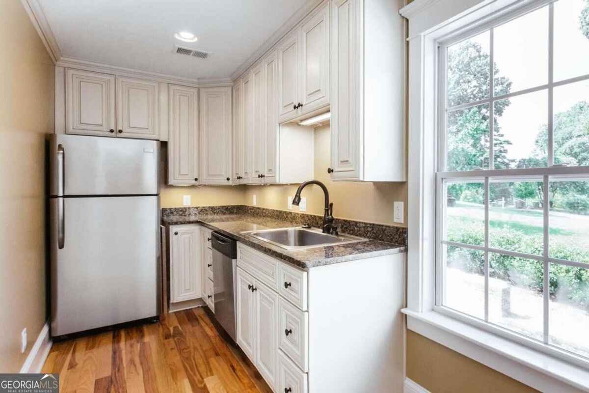 Small secondary kitchen or utility area highlights a compact design with stainless steel appliances.