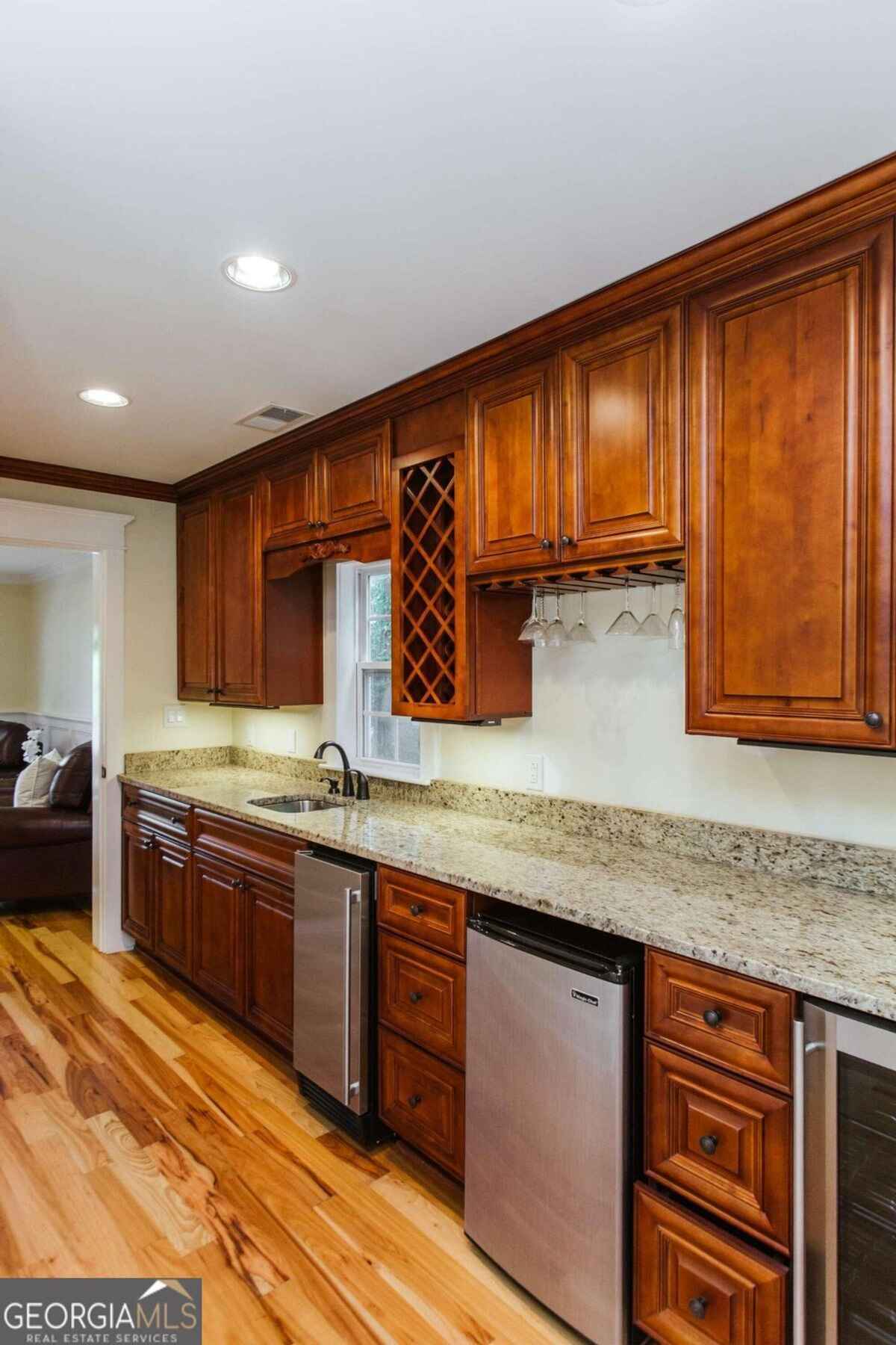 Bar area presents rich wooden cabinetry, a wine rack, and granite countertops.