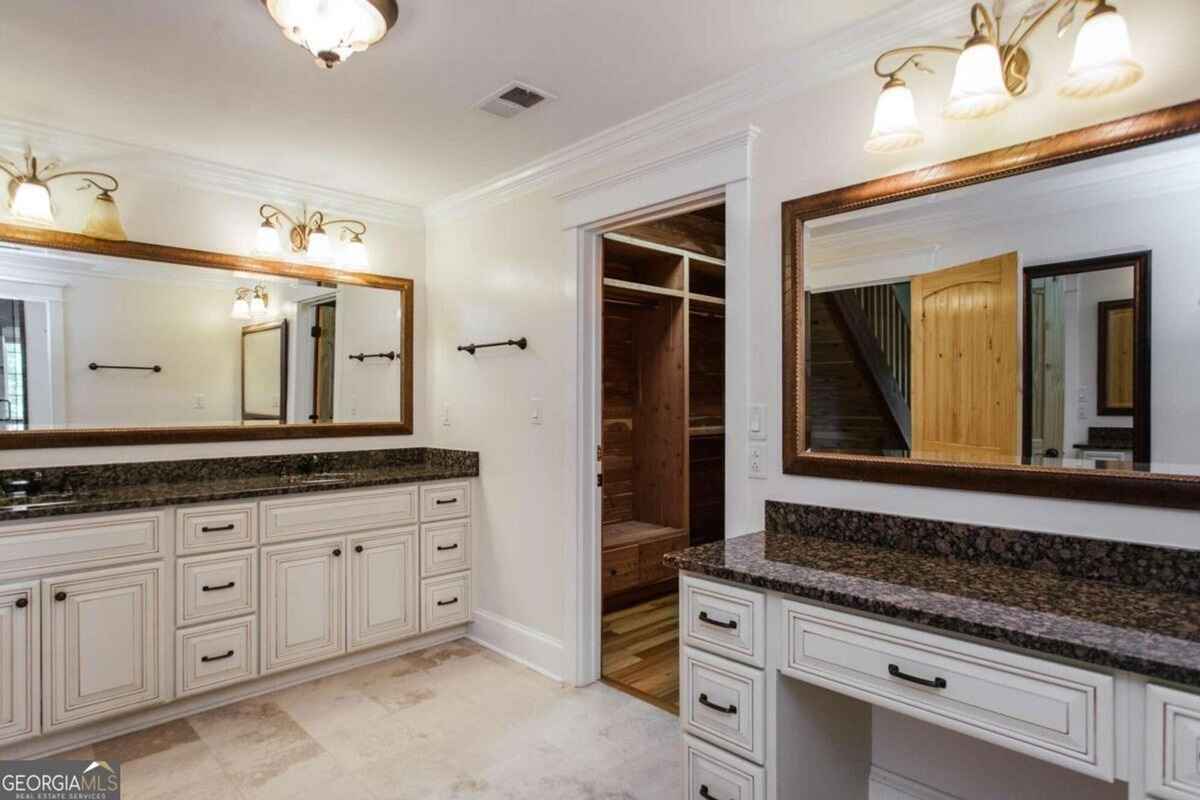 Double vanity bathroom features granite counters, ample storage, and access to a walk-in closet.