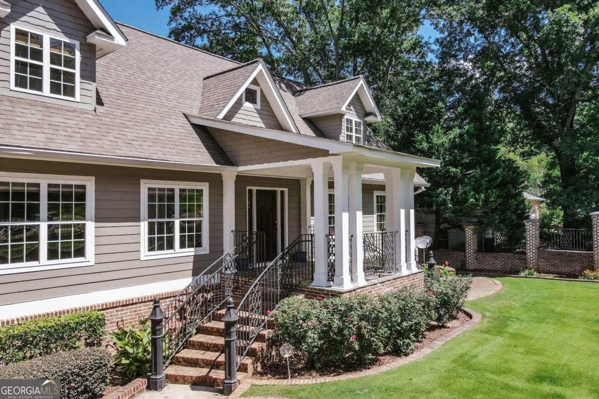 Angled perspective highlights the front landscaping, brick accents, and wrought iron railings leading to the entrance.