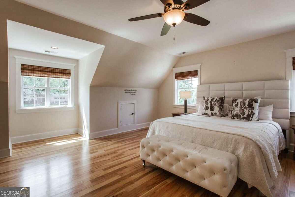 Spacious bedroom highlights a neutral color palette with a ceiling fan and large windows for natural light.