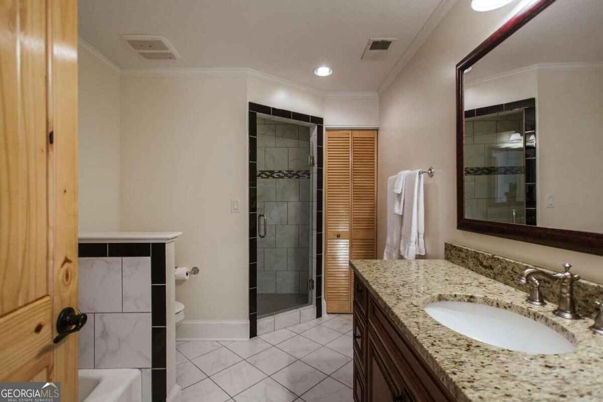 Bathroom includes granite countertops, a tiled shower, and wood cabinetry.