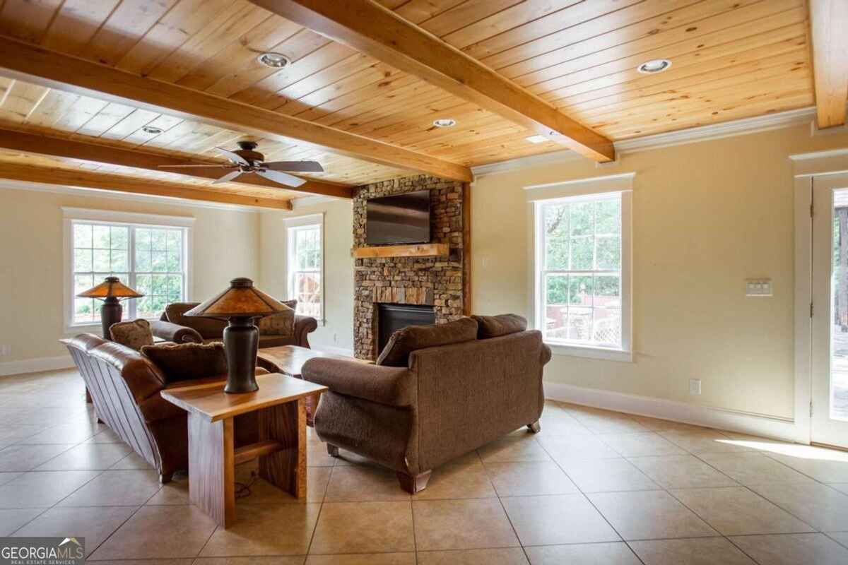 Living room features a stone fireplace, wooden beam ceiling, and tile flooring.