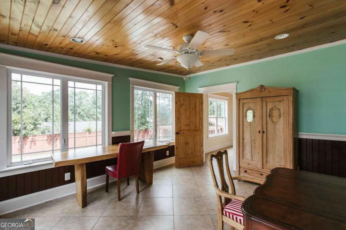 Sunroom includes a wooden ceiling, large windows, and space for multiple seating arrangements.