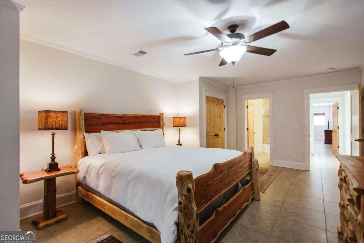 Guest bedroom showcases custom wooden bed frame, neutral walls, and matching wooden doors.