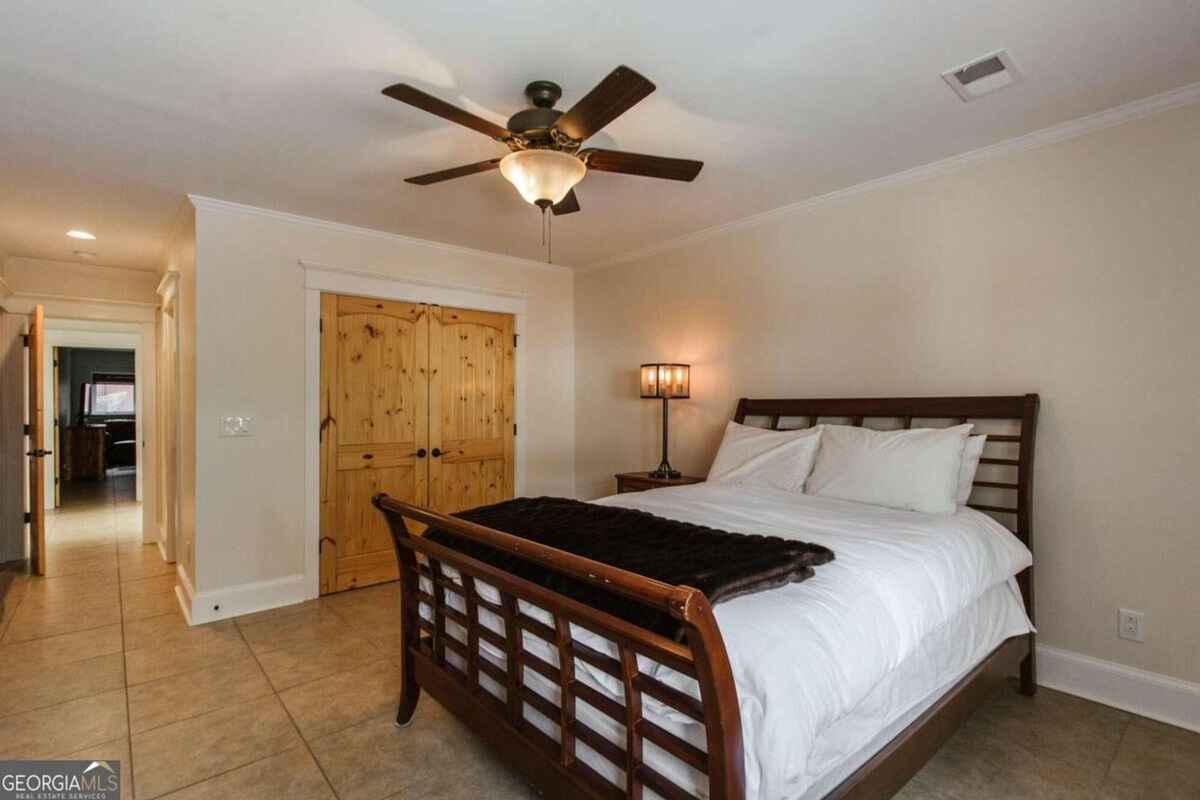 Bedroom includes a wooden bed frame, ceiling fan, and tile flooring.