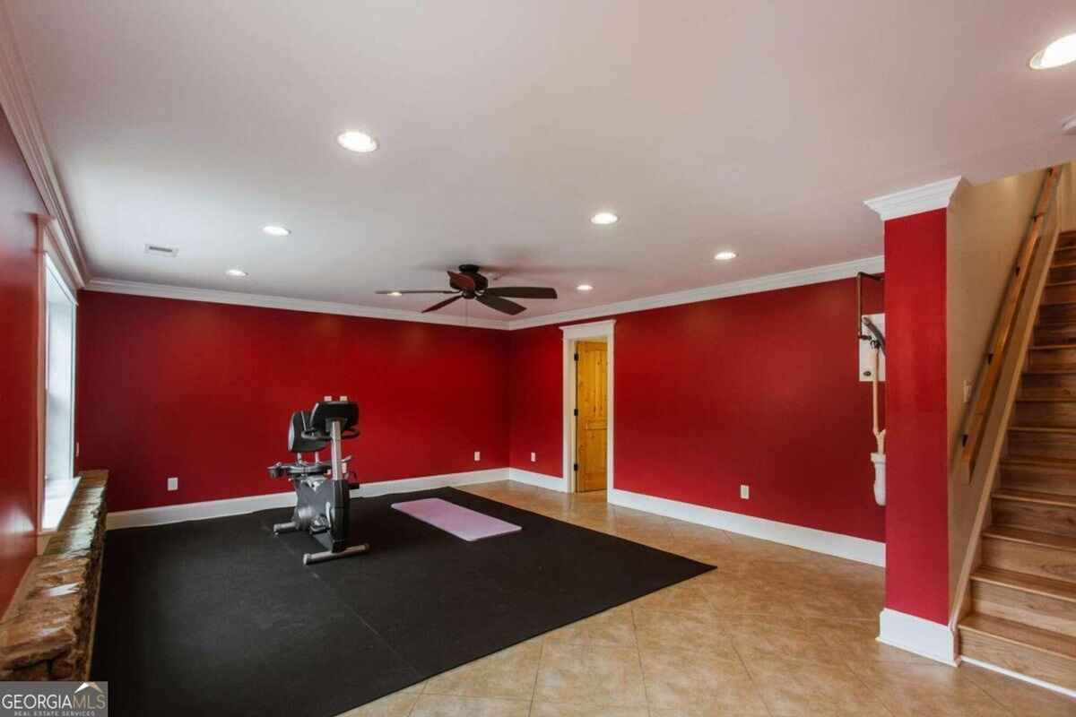 Home gym showcases a bright red accent wall, recessed lighting, and exercise equipment.