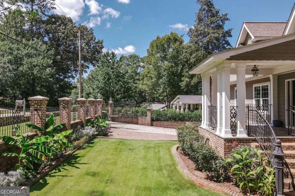 Side yard includes a brick-lined walkway, lush greenery, and a view of the fenced property line.