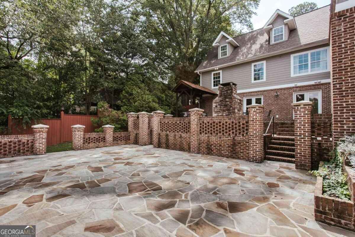 Backyard area displays an expansive stone-paved patio bordered by brick columns.