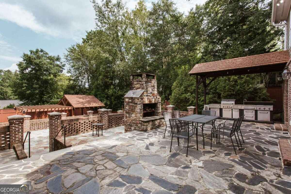 Outdoor space features a built-in stone fireplace, grilling station, and seating area.