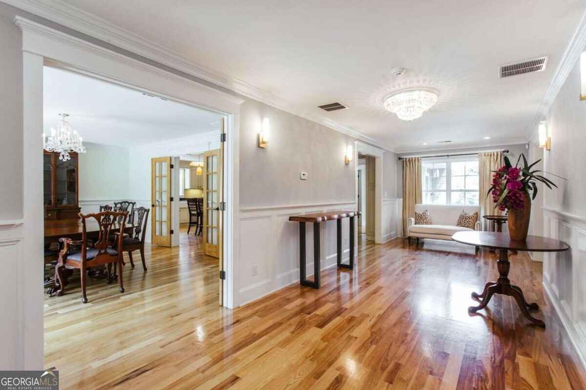 Interior hallway features hardwood flooring, neutral walls, and access to adjoining rooms with natural light.