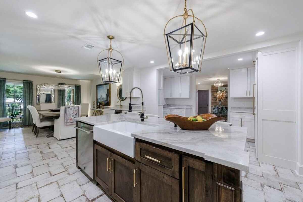 Kitchen layout showcases a large island with a farmhouse sink, marble countertops, and pendant lantern lighting.