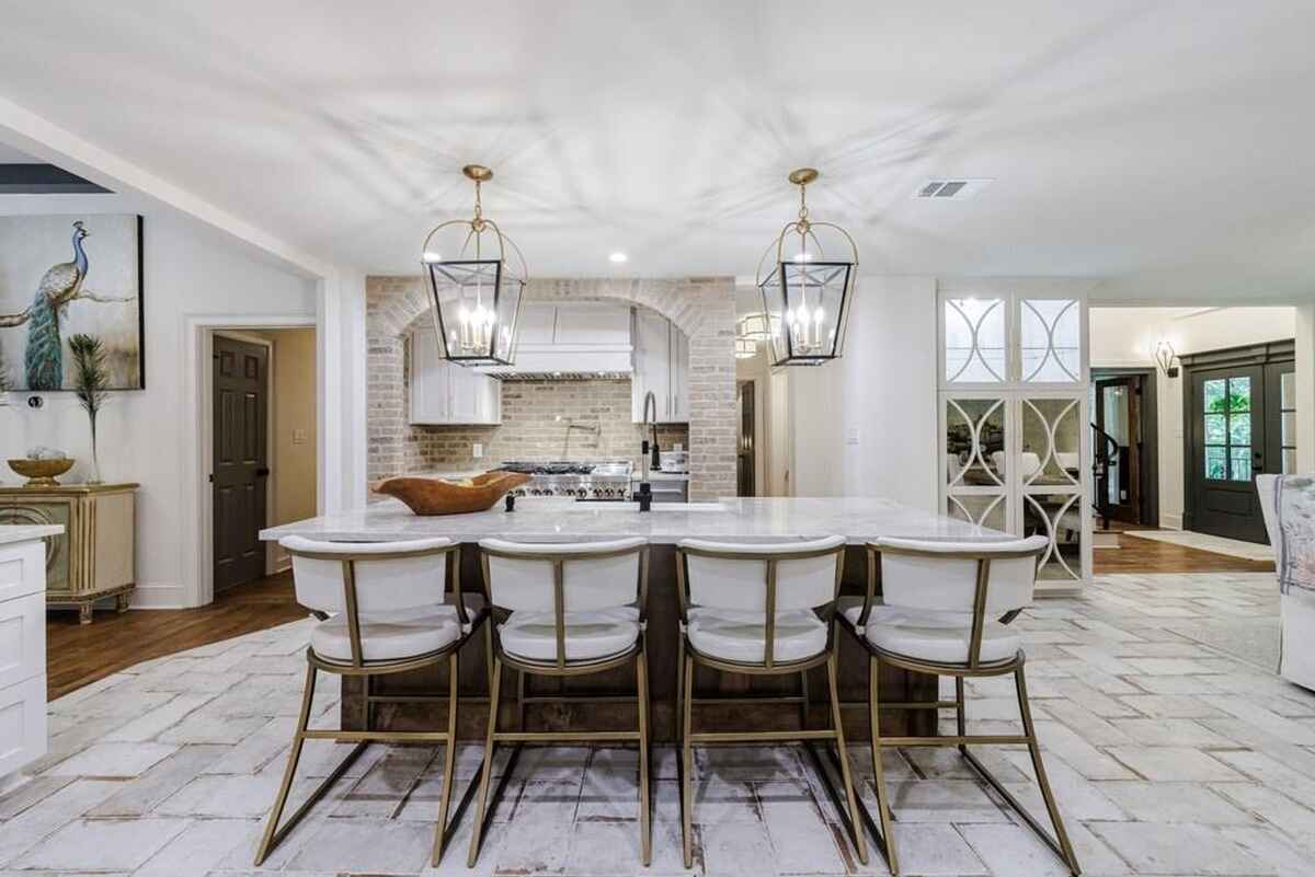 Kitchen features a large island with barstools, marble countertops, and lantern-style pendant lights.