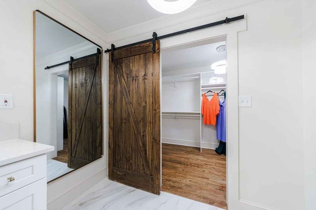 Closet area includes a large mirror, sliding wooden barn doors, and visible shelving for clothing storage.