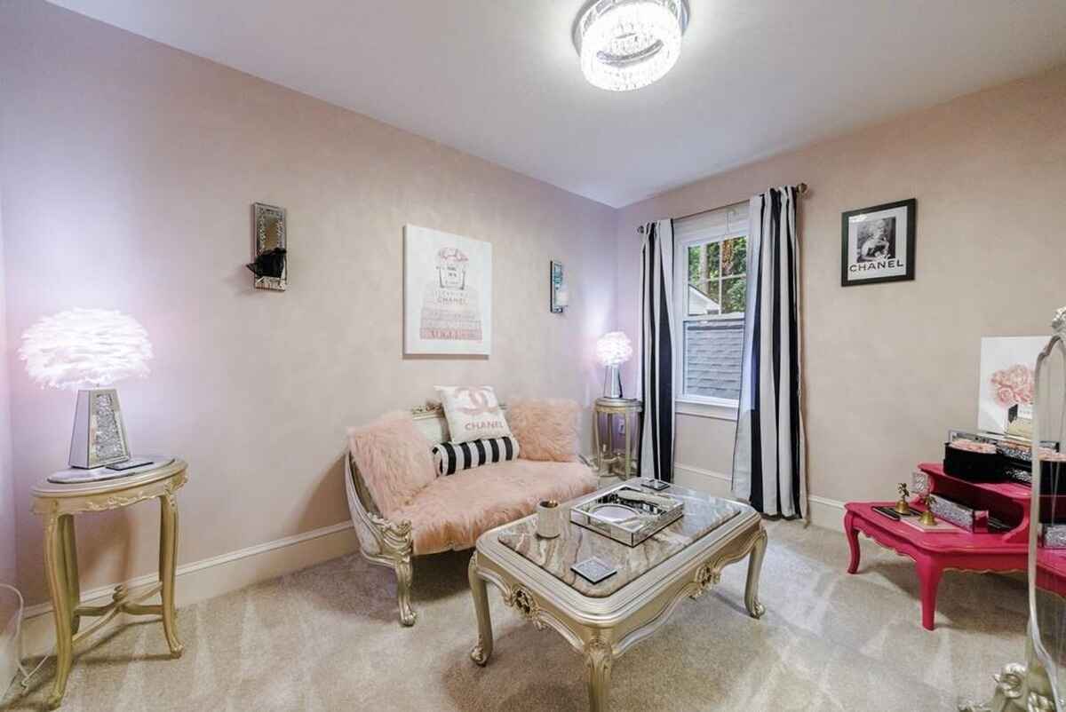 Sitting area includes a pink and gold color scheme, decorative furniture, and striped black-and-white curtains.