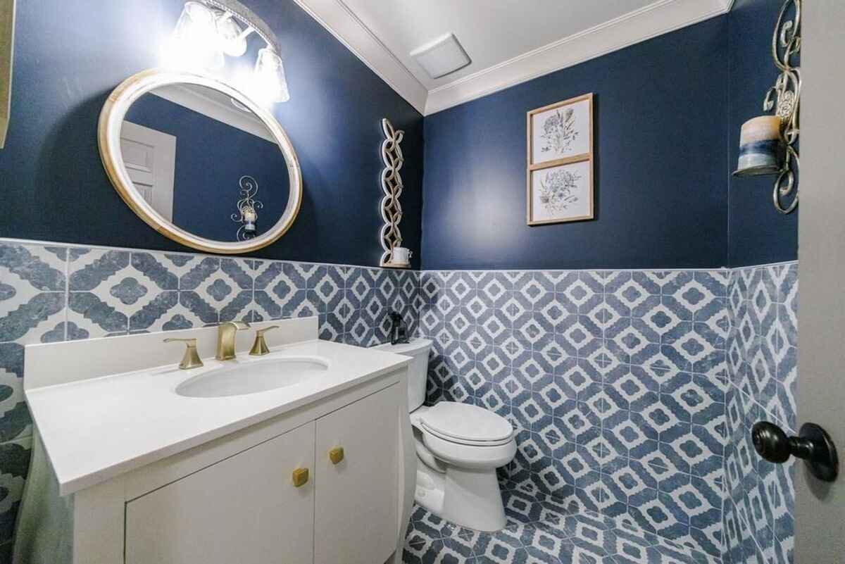 Navy blue walls, patterned tile, and a white vanity create a stylish powder room.