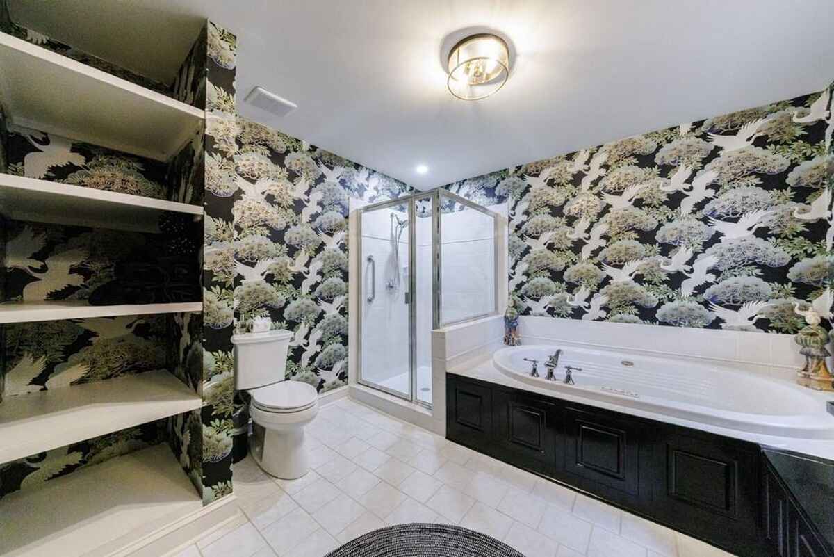 Crane-patterned wallpaper, a soaking tub, and white tile flooring create a spa-like bathroom.