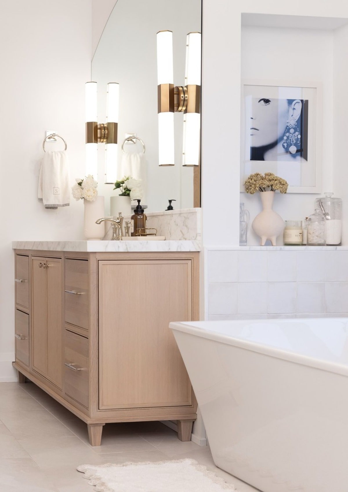 This serene bathroom features a neutral color palette and minimalist design, creating a calming and spa-like atmosphere. The light wood vanity and freestanding tub add a touch of understated elegance.