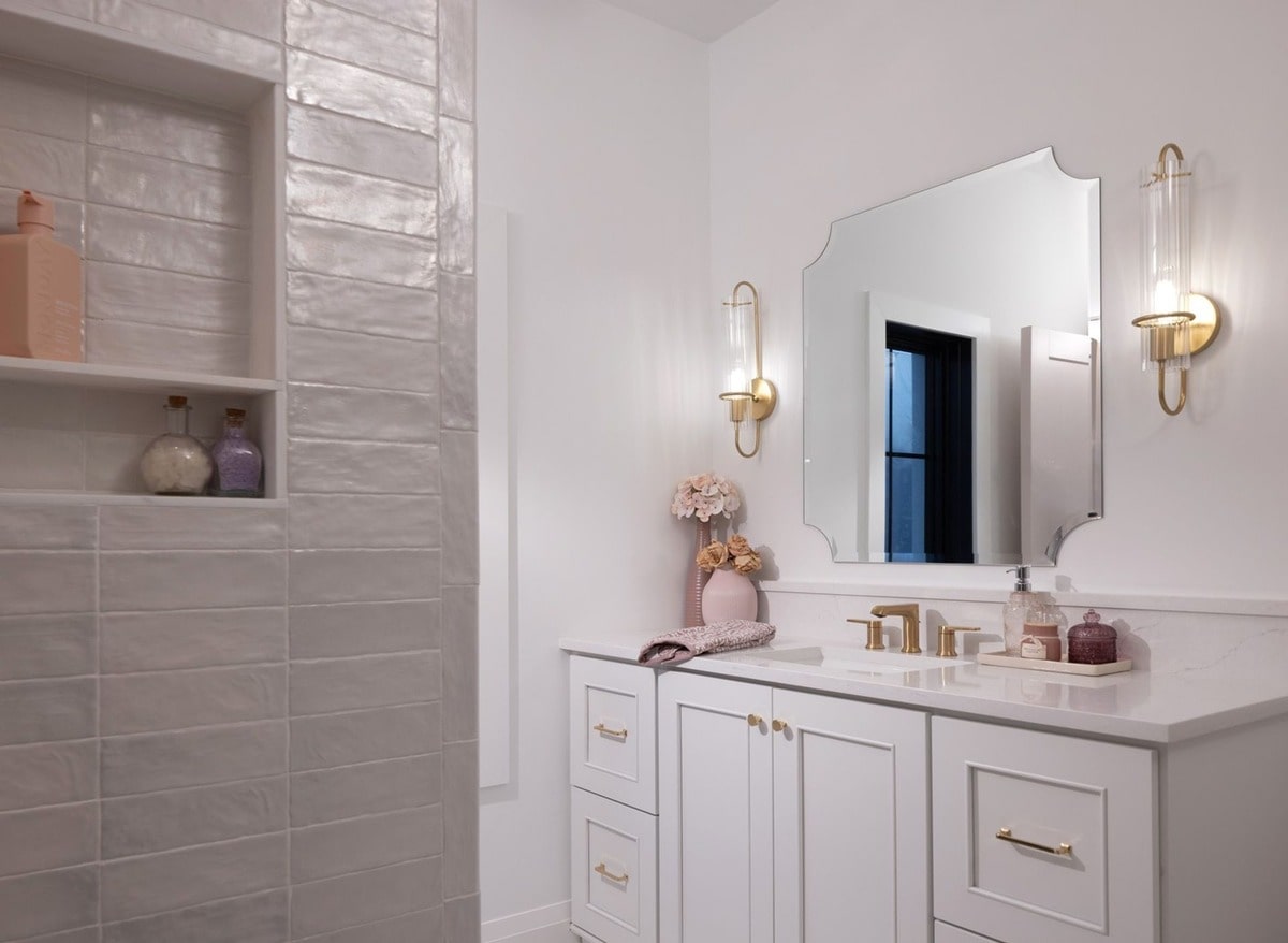 The bathroom's design showcases attention to detail, from the subtle texture of the wall tiles to the carefully chosen gold hardware. The recessed shower niche and stylish lighting fixtures enhance both functionality and aesthetics.