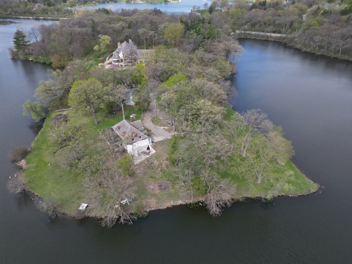 The property features a striking juxtaposition of architectural styles, with a grand, possibly historic main house contrasting with a more contemporary secondary building. The island setting enhances the property's unique character and secluded ambiance.