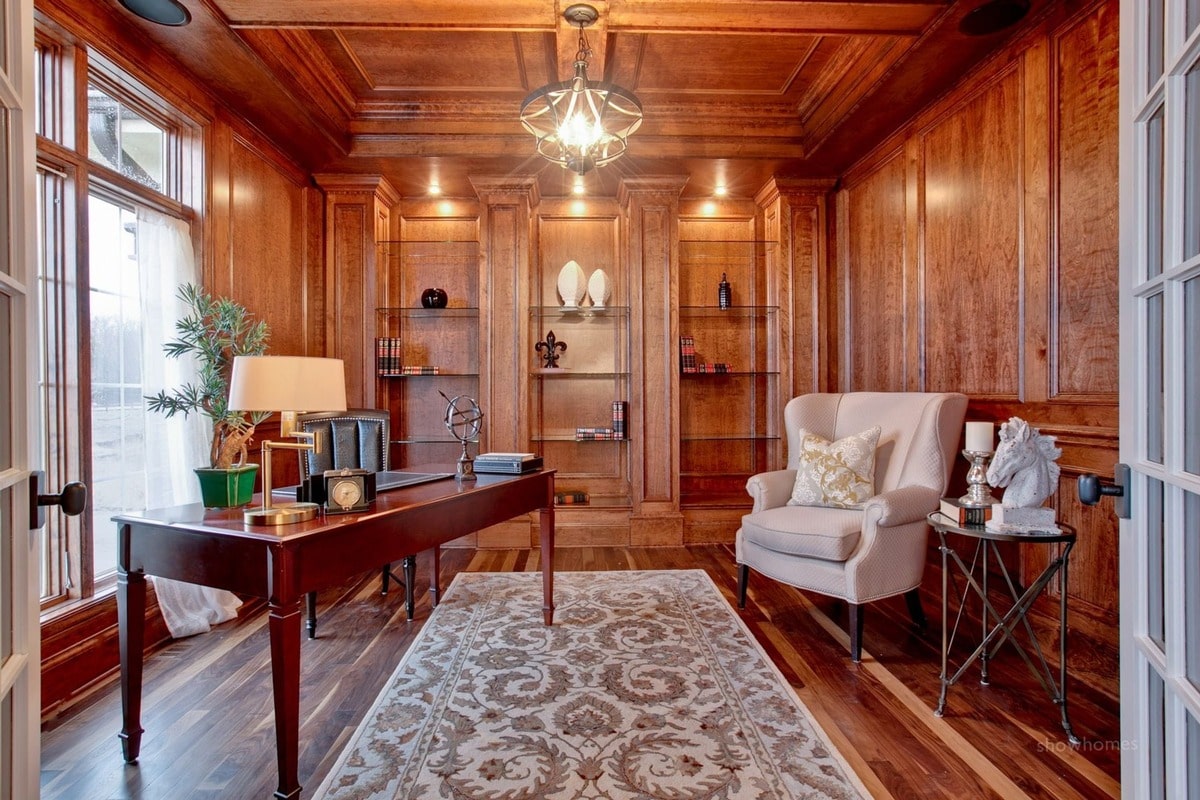 Warm wood tones and intricate detailing define this inviting home office, creating a space that is both functional and aesthetically pleasing. The combination of natural light, comfortable seating, and a patterned rug adds to the room's overall warmth and charm.