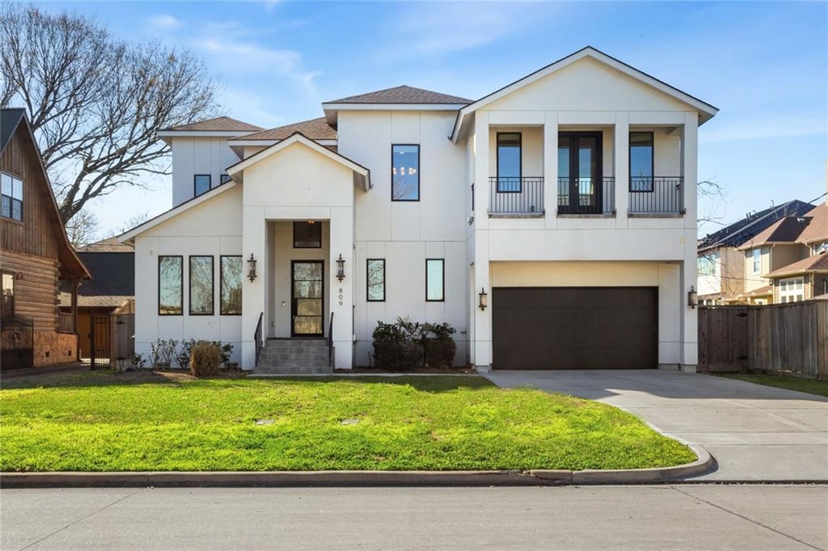 Exterior view of a modern two-story house with a clean white facade, front porch, and attached two-car garage.