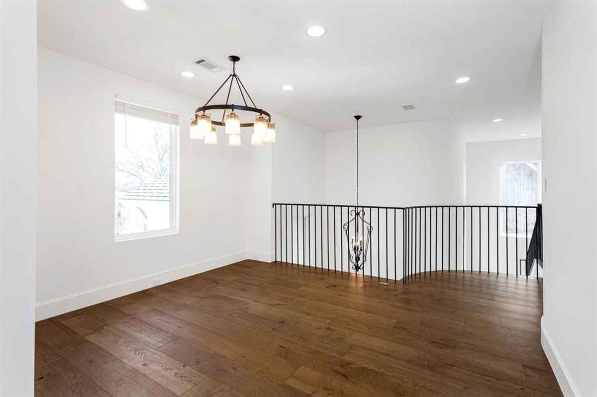 Upper landing area includes hardwood floors, a modern chandelier, and a railing overlooking the stairway.