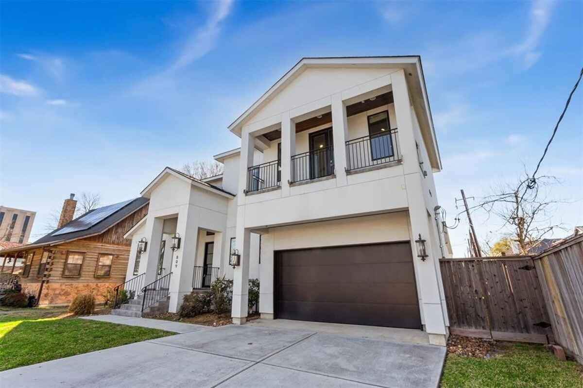 Modern two-story home features a double garage, balcony, and front entryway with steps leading to the porch.