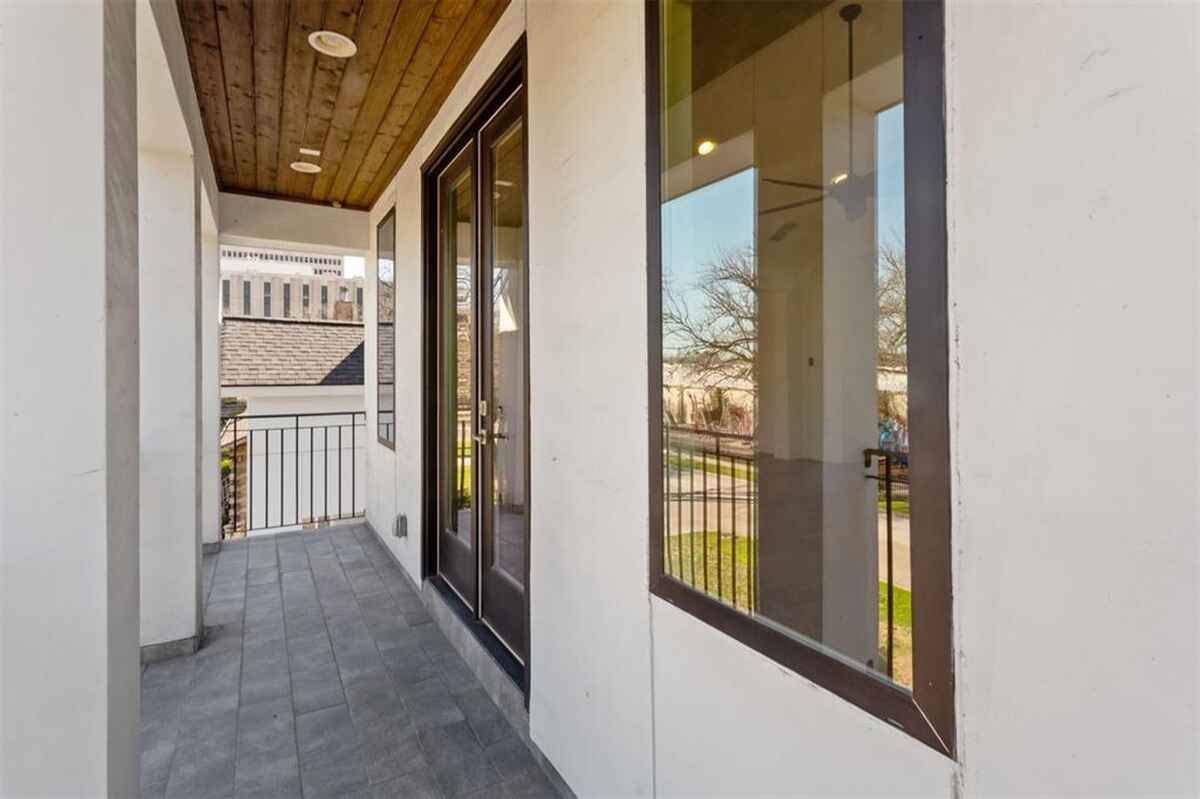 Balcony features tiled flooring, wooden ceiling paneling, glass doors, and metal railing overlooking the front yard.