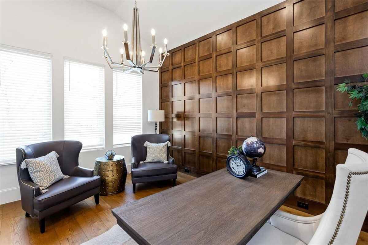 Office features wood panel walls, a chandelier, leather chairs, and a wooden desk with decorative accents.