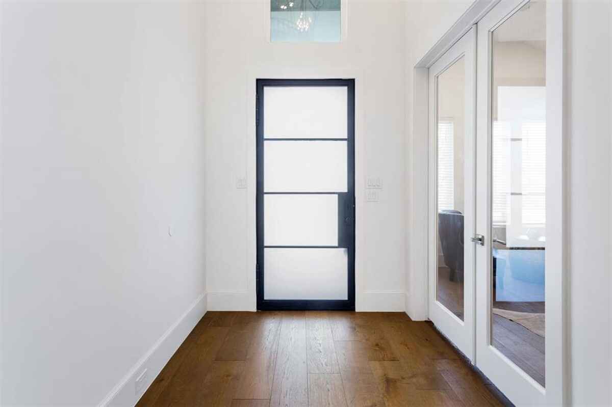 5. Entryway features a frosted glass door with a black frame, hardwood flooring, and adjacent double glass-panel doors.