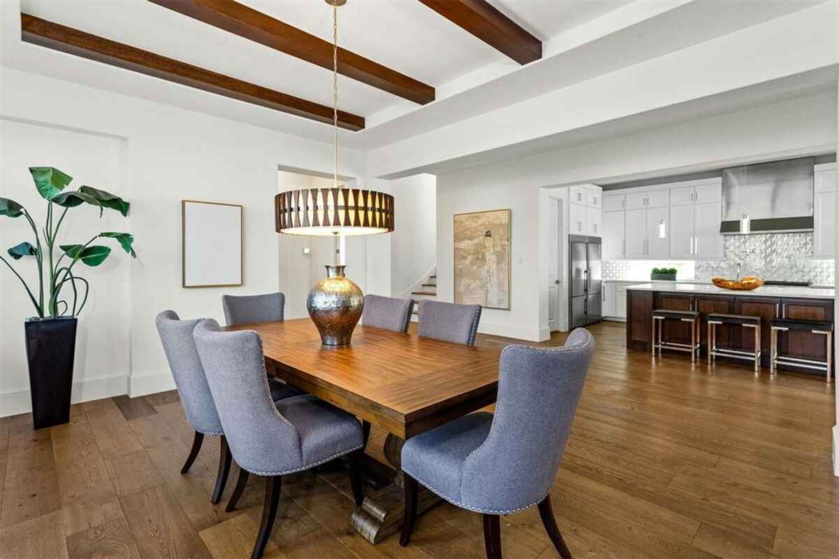 Kitchen includes white cabinetry, a center island with seating, stainless steel appliances, and a decorative tile backsplash.