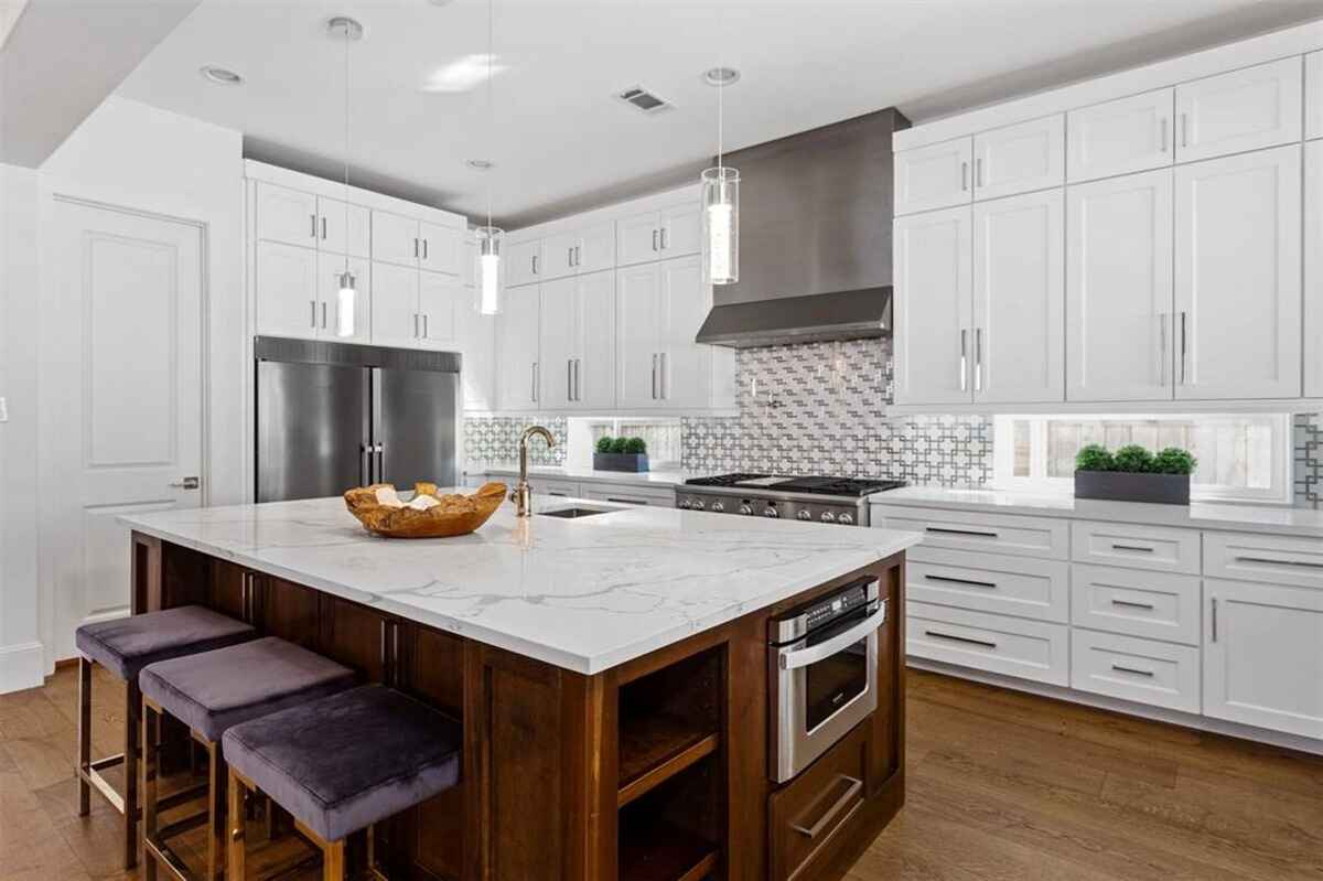 Kitchen includes a large marble countertop island, stainless steel appliances, and pendant lighting.