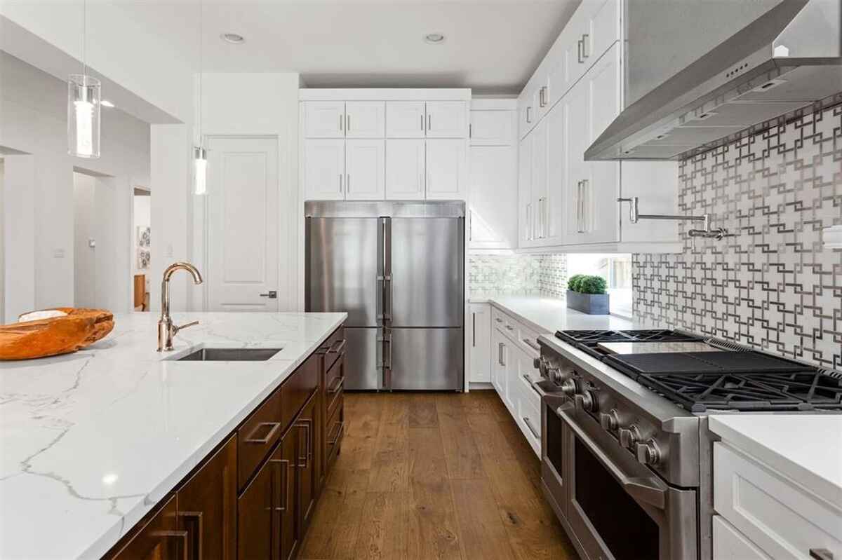 Kitchen features white cabinetry, a stainless steel refrigerator, and a decorative backsplash.