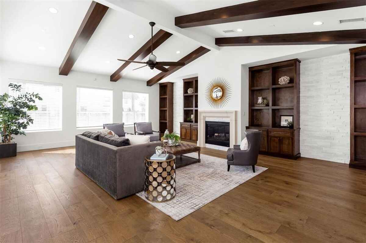 Living room includes a fireplace, built-in shelving, exposed wooden beams, and large windows.