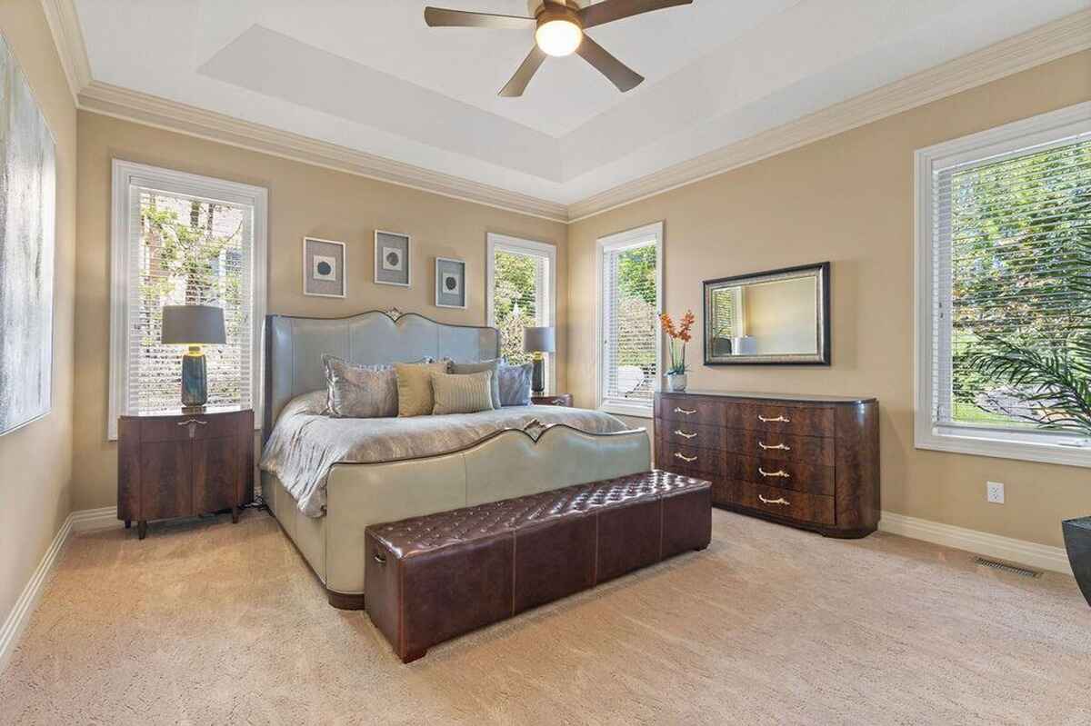 Elegant bedroom featuring a tray ceiling, contemporary furniture, and large windows with natural light