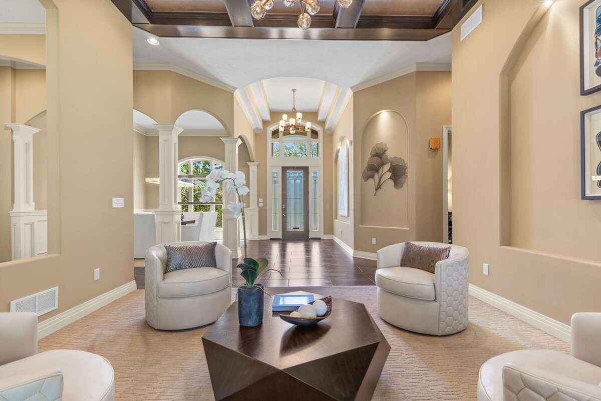 Open living area with vaulted ceilings, intricate columns, and an inviting seating arrangement under a stylish chandelier.