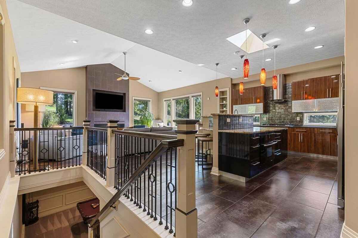 Stairway leading to a lower level with a view of the open-plan kitchen, living room, and large windows inviting abundant natural light.