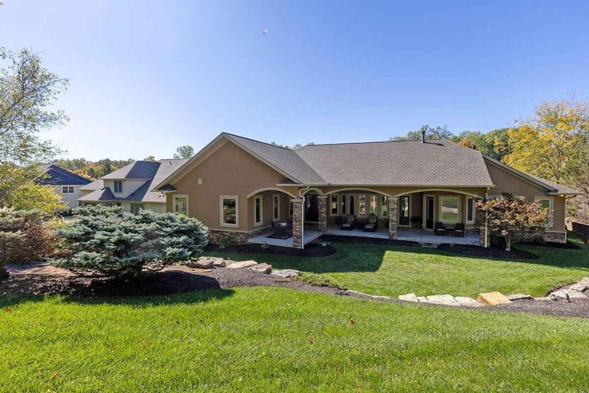 Rear view highlights a spacious patio with covered seating areas and well-manicured green surroundings.