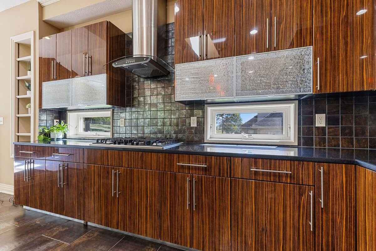 Sleek modern kitchen with glossy wooden cabinetry, a central island, and vibrant pendant lighting.