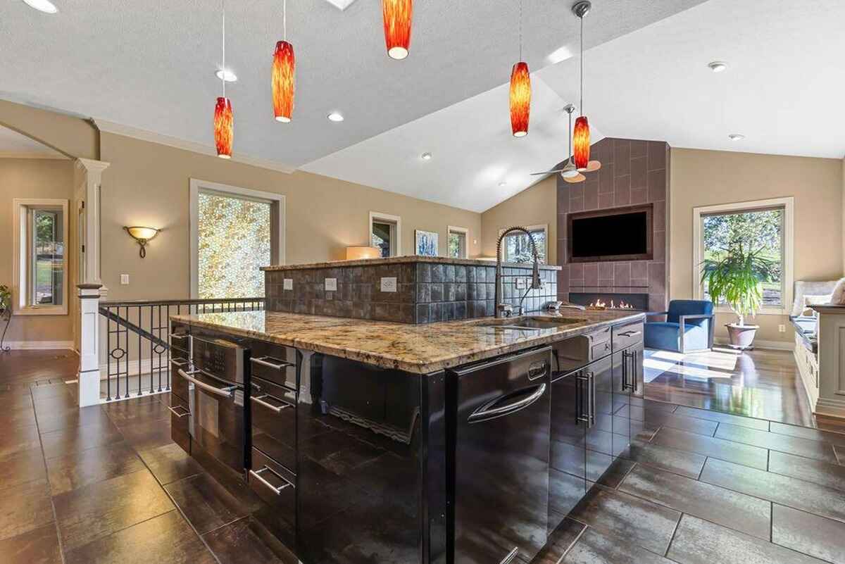 Open-concept kitchen showcases a large central island with granite countertops, modern pendant lighting, and a built-in sink.