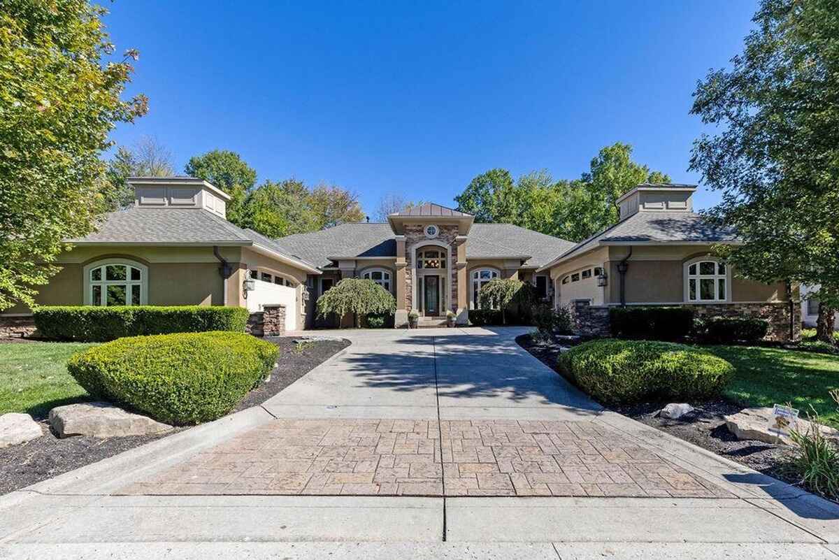 Driveway leads to the house with a symmetrical facade, central entryway, and dual garages on either side.